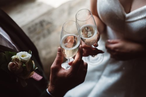 Близък план на семейна двойка, препичаща чаши за шампанско на сватбено тържество.  Ръцете булката и младоженеца звънят на чаши на сватбен прием.