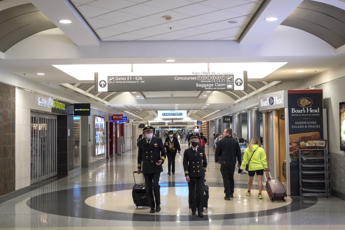Pilots and passengers wear face masks as they walk inside the terminal at Hartsfield-Jackson Atlanta International Airport walk inside a terminal.