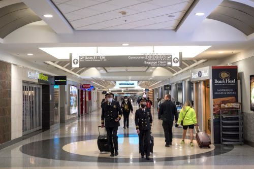 Pilots and passengers wear face masks as they walk inside the terminal at Hartsfield-Jackson Atlanta International Airport walk inside a terminal.