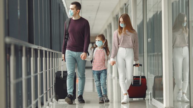 A couple with a young child board a flight while wearing face masks in an airport