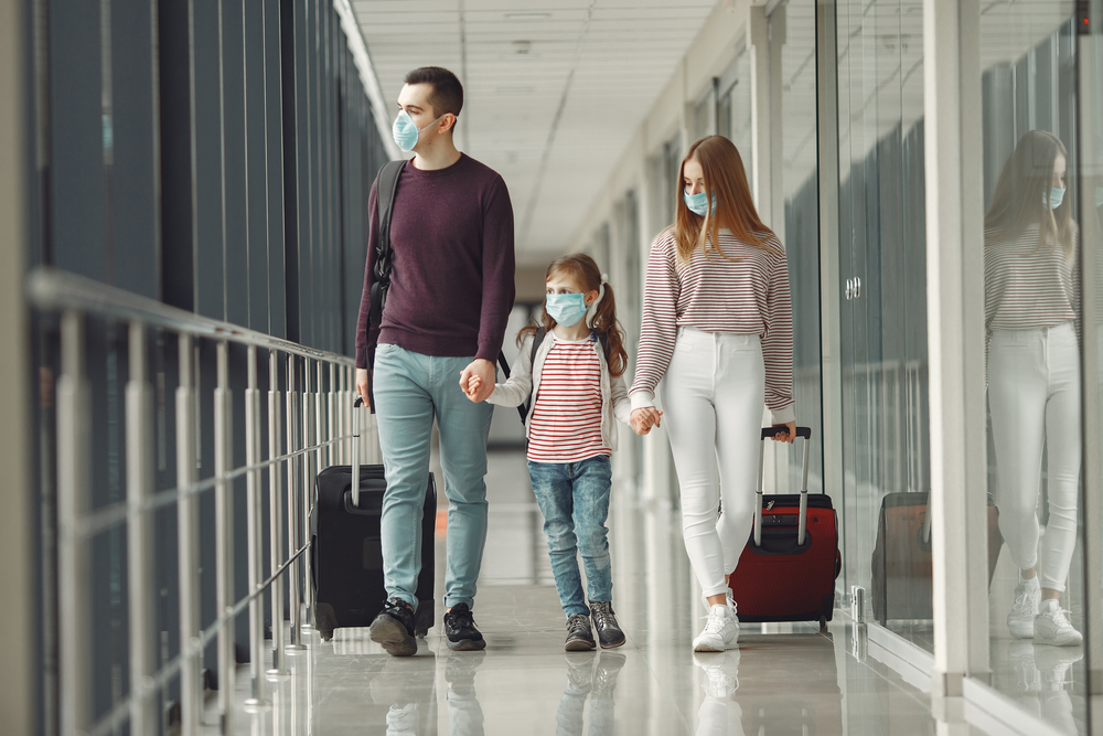 A couple with a young child board a flight while wearing face masks in an airport