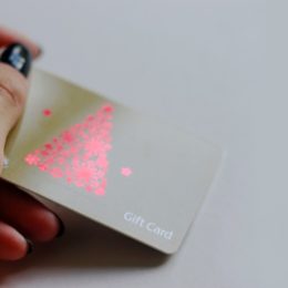 LONDON, UK, March 2019 Woman's holding Sainsbury's Gift Card, wine illustration, red christmas tree