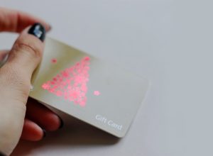 LONDON, UK, March 2019 Woman's holding Sainsbury's Gift Card, wine illustration, red christmas tree