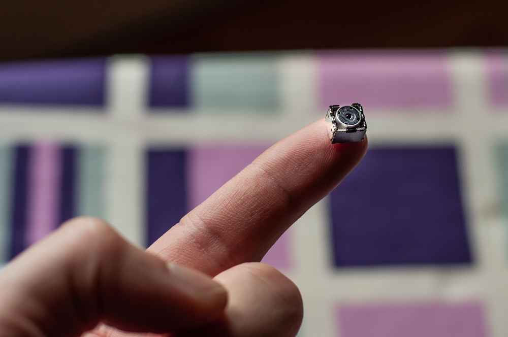 A tiny camera that can be hidden resting on someone's finger