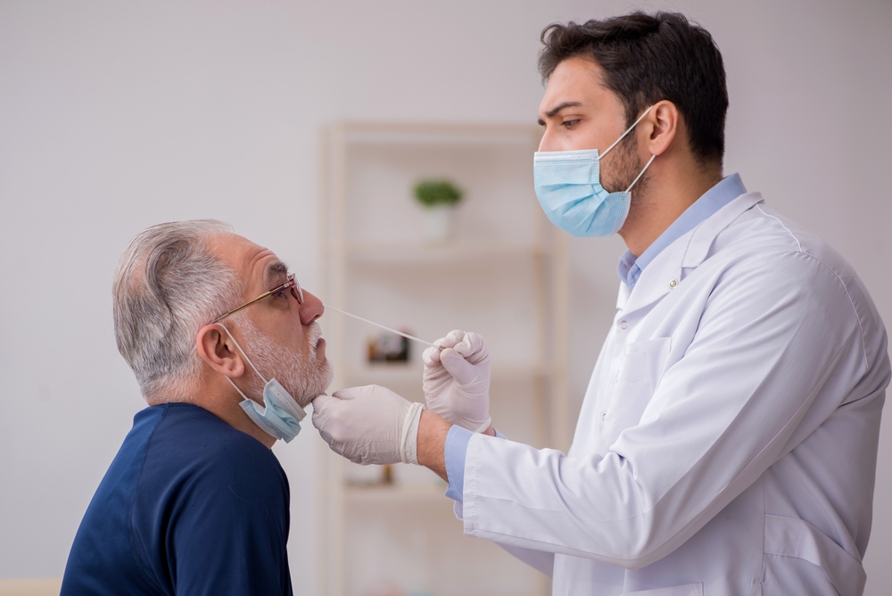 A senior man getting a COVID nasal swab test from a doctor or healthcare worker