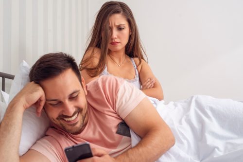 Girlfriend looking angry at boyfriend on phone