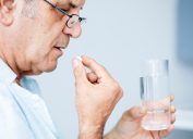 A senior man taking medication with a glass of water