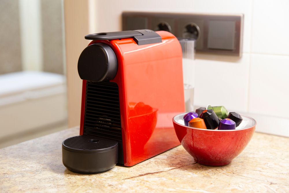 A Nespresso coffee maker with a bowl of pods next to it