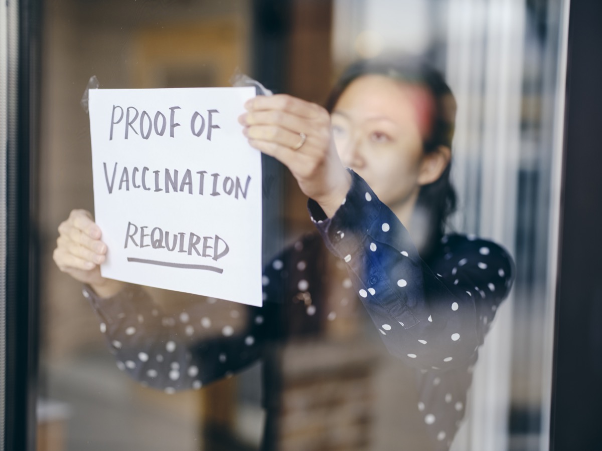 Собственик на бизнес, който поставя табела, изискваща доказателство за ваксинация.
