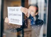 A business owner putting up a sign requiring proof of vaccination.
