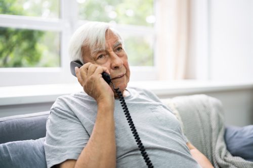 Ηλικιωμένος άνδρας μιλάει στο σταθερό τηλέφωνο