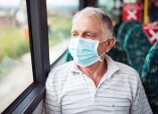 Senior man with respiratory mask traveling in the public transport by bus