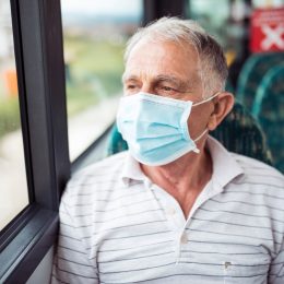 Senior man with respiratory mask traveling in the public transport by bus
