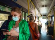 Woman in medical mask with mobile phone in the bus.