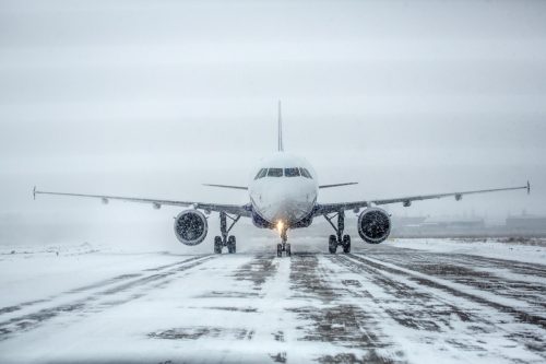 Airliner on runway in blizzard. Aircraft during taxiing during heavy snow. Passenger plane in snow at airport. Modern twin-engine passenger airplane taxiing for take off at airport during snow blizzard