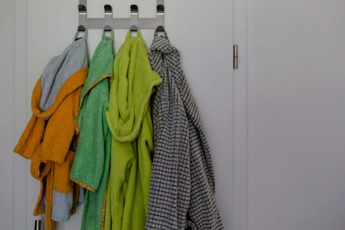 four bathrobes hang next to each other on the bathroom door