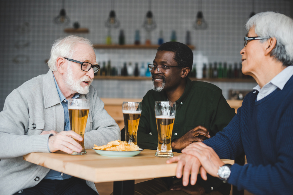 A group of elderly men drinking beer in a bar