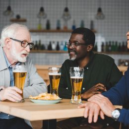 A group of senior men drinking beer at a bar
