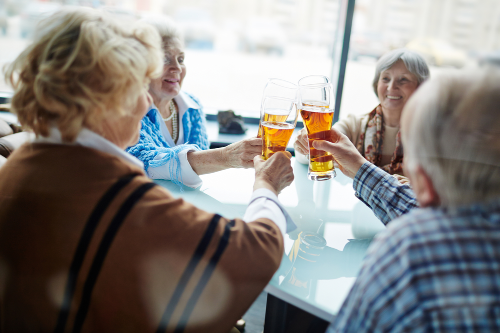 A group of senior women sitting at a table drinking beer together
