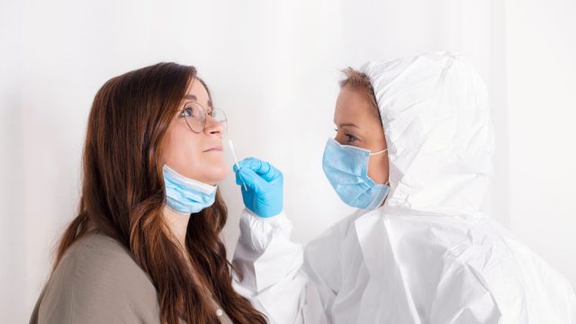 A woman getting a nasal swab from a healthcare worker as part of a COVID-19 test