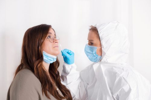 A woman getting a nasal swab from a healthcare worker as part of a COVID-19 test