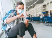 A woman wearing a face mask using hand sanitizer in an airport terminal