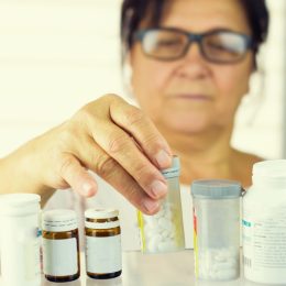 older woman looking at prescriptions in medicine cabinet