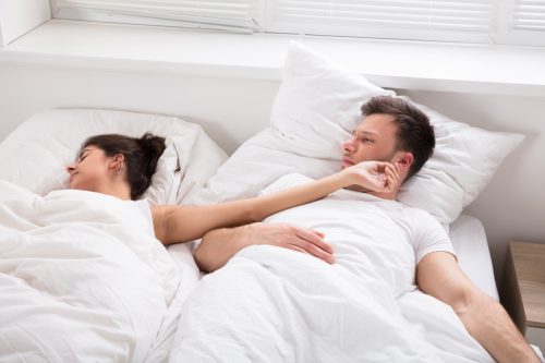 Woman moving arm while sleeping next to man