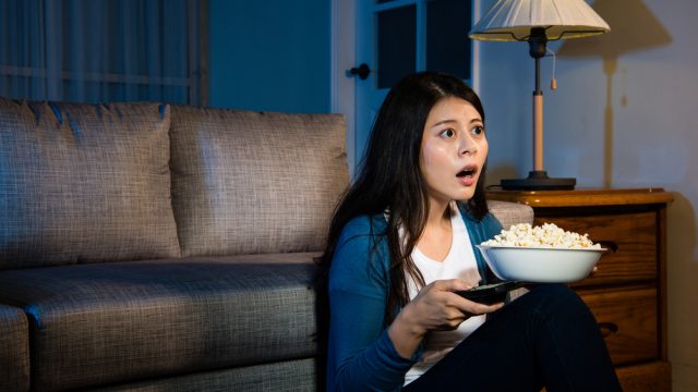 A young woman watching TV with a surprised or confused look on her face