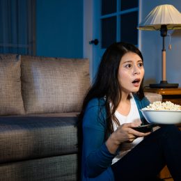 A young woman watching TV with a surprised or confused look on her face