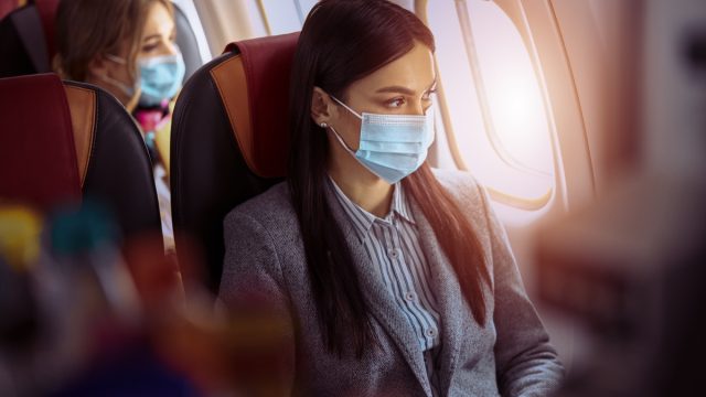 Woman is sitting in mask before flying on plane