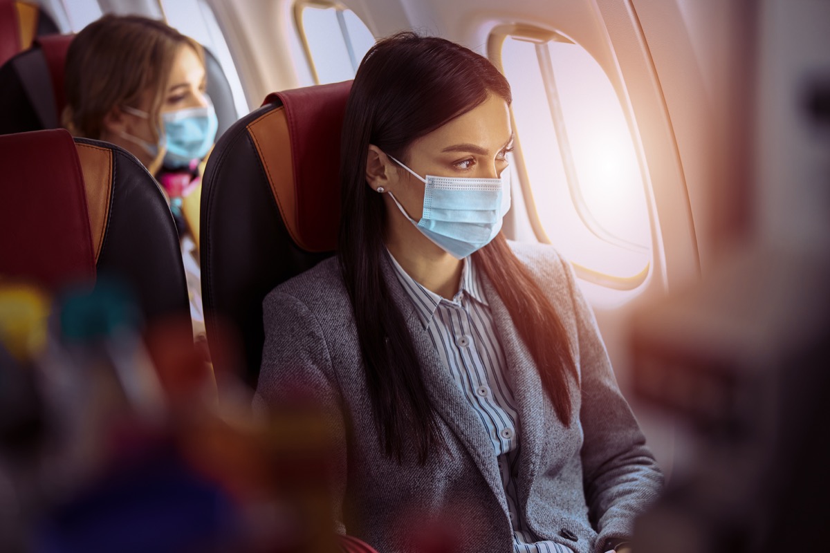 New order in airplane. Woman is sitting in mask before fly