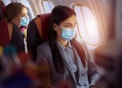 Woman is sitting in mask before flying on plane