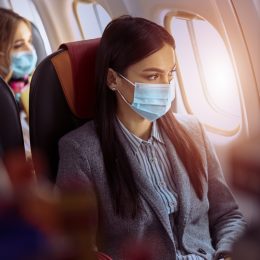 New order in airplane. Woman is sitting in mask before fly