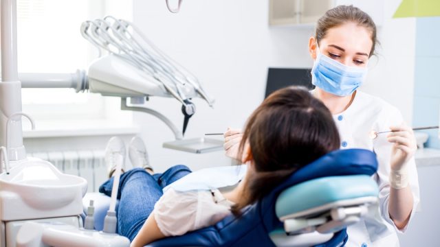 Dentist treats teeth girl lying in the dental chair