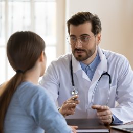 Young male doctor talking to female patient