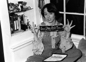 mackenzie phillips holding a placard that says one day at a time