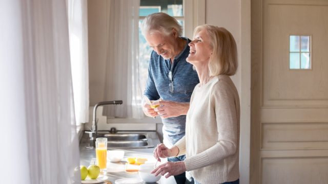 Older couple talking and laughing in kitchen