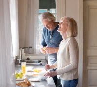 Older couple talking and laughing in kitchen