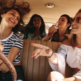 Group of women driving in a car and singing along to music