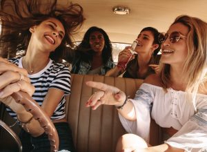 Group of women driving in a car and singing along to music