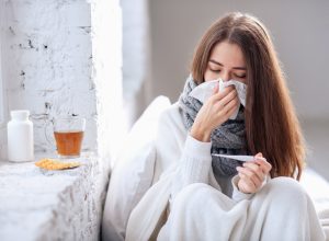 Woman with flu taking temperature