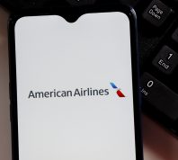 The American Airlines logo on a smartphone screen sitting next to a keyboard