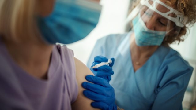 Closeup side view of a young woman having Covid-19 vaccine.
