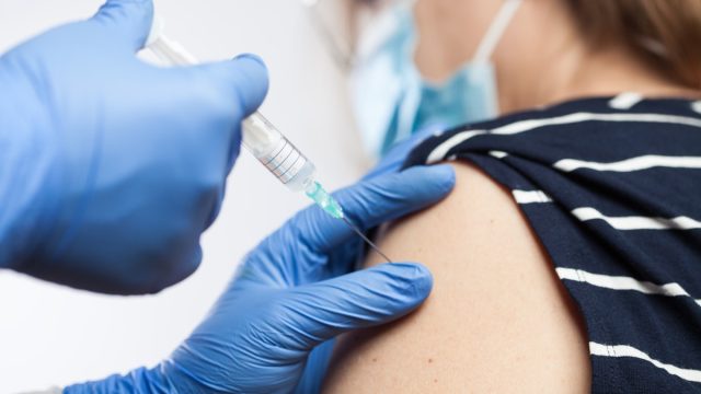 Closeup of medical worker's hands in blue protective gloves injecting vaccine booster shot into elderly patient's shoulder,Coronavirus vaccination against COVID-19 virus disease,immunity certificate