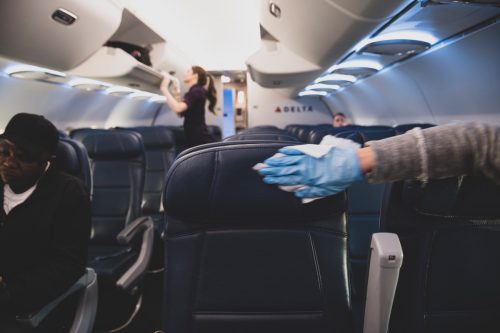 On a Delta flight from New York's Laguardia Airport to Atlanta, a passenger who has just boarded wears a plastic glove while using a wipe to disinfect the airplane seats and armrests on her row. (March 21, 2020)