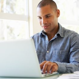Young Man Using Laptop At Home Looking At The Screen