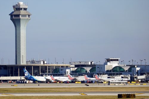 Outside view of Terminal 3 at O'Hare International Airport where American Airlines and Alaska Airlines planes are parked at the gates on a busy holiday travel day.