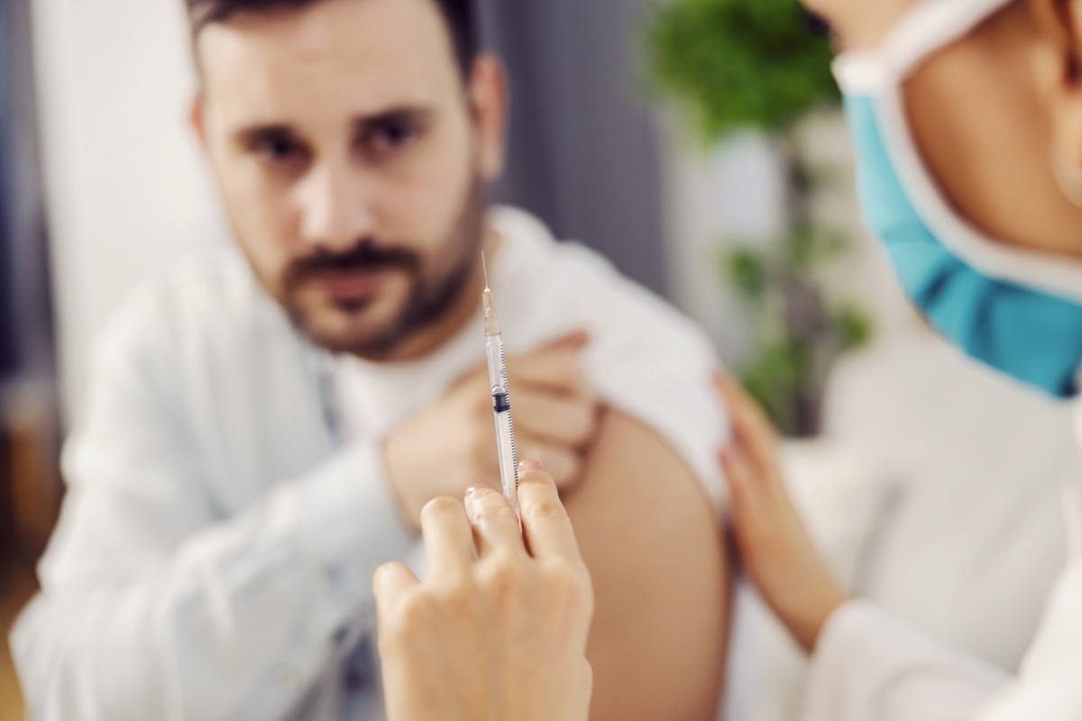 Close up of a nurse holding a covid 19 vaccine and comforting a scared man at his home.