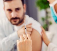 Close up of a nurse holding a covid 19 vaccine and comforting a scared man at his home.